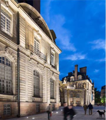Sur la Grande Île de Strasbourg, des passants remarquent l'éclairage architectural devant un bâtiment illuminé par l'éclairage Philips