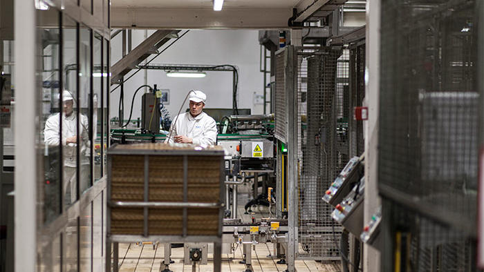 Un employé au travail dans l’usine Hero, mise en lumière par un éclairage LED Philips à économie d’énergie, prévu pour l’industrie alimentaire