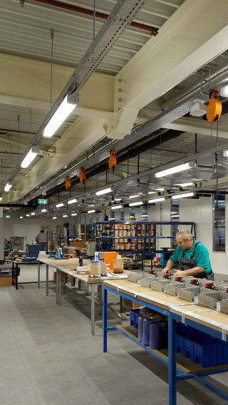 Ein Mitarbeiter arbeitet im Produktionsbereich des Venco Campus, der dank der Philips Industriebeleuchtung hell erleuchtet ist