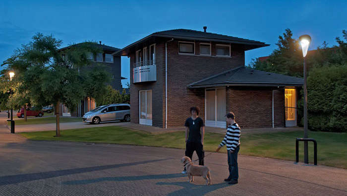 Deux personnes promenant un chien dans une rue mise en lumière par une solution d'éclairage urbain Philips  