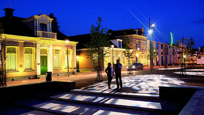 Un couple marchant sur une place embellie et mise en lumière par Philips Lighting