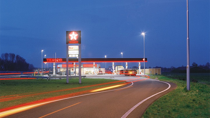 Une station Texaco à côté de l’autoroute, éclairée de manière attractive au crépuscule – un éclairage extérieur attractif