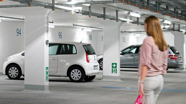 Un femme marche vers sa voiture dans un parking souterrain bien éclairé 