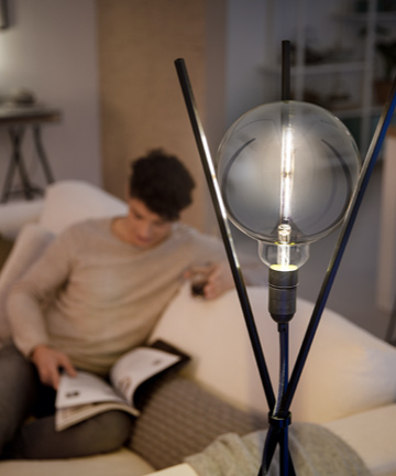 Homme lisant à côté d'une ampoule LED Philips au design moderne 