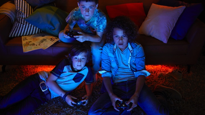 3 Jungen, die Videospiele mit Ambienterbeleuchtung spielen