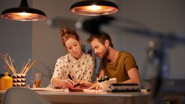 Zwei Personen, die an einem gut beleuchteten Schreibtisch einen Lichtplan erstellen