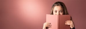 „Ein junges Mädchen, das über ein rosafarbenes Buch blickt, vor einem sanft beleuchteten LED-Hintergrund, der eine warme, gleichmäßige Beleuchtung für eine angenehme Leseumgebung bietet.“
