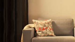 Salon confortable avec lampe de table LED moderne, éclairant un canapé gris et créant une ambiance chaleureuse pour la détente à la maison.