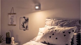 Chambre élégante avec spot LED réglable créant une ambiance chaleureuse, illuminant une literie géométrique et une décoration minimaliste.