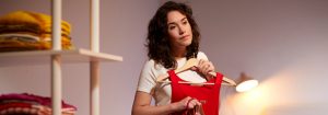 "Une lampe de bureau à LED chaude éclaire une femme en train de choisir ses vêtements, mettant en évidence l'efficacité énergétique de l'éclairage d'appoint dans l'espace de rangement de la maison."