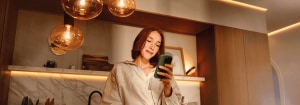"L'éclairage LED connecté crée une ambiance violette dans le salon, tandis qu'un couple se détend sur le canapé tout en contrôlant l'éclairage personnalisable via un smartphone. »