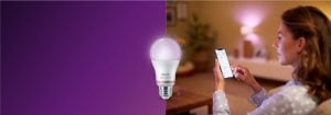 "Une femme contrôle l'éclairage LED connecté via une application pour smartphone, créant une ambiance chaleureuse dans un salon confortable avec la technologie de la maison connectée. »